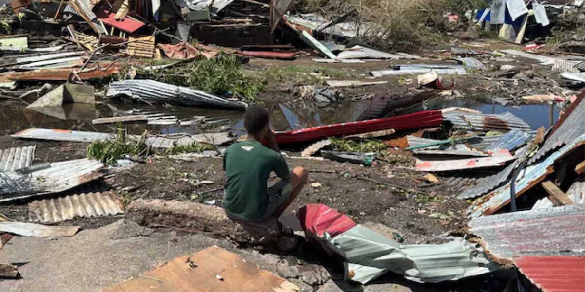 A Boy Sitting Near The Damaged Houses